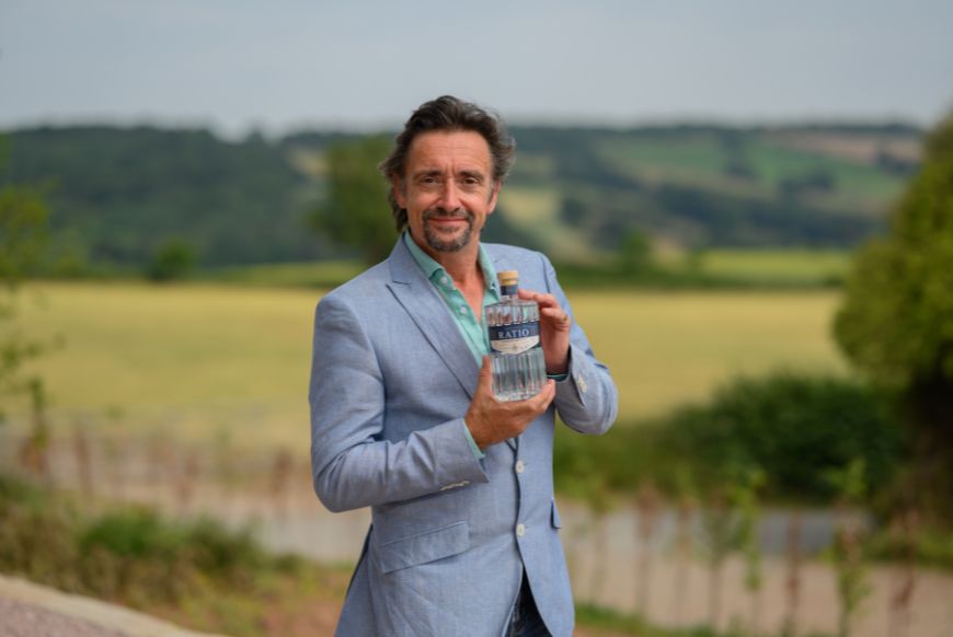 Man (Richard Hammond) standing in english countryside holding a bottle of Gin labellled 'Ratio'